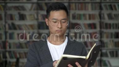 年轻人在书架的背景上读一本便条